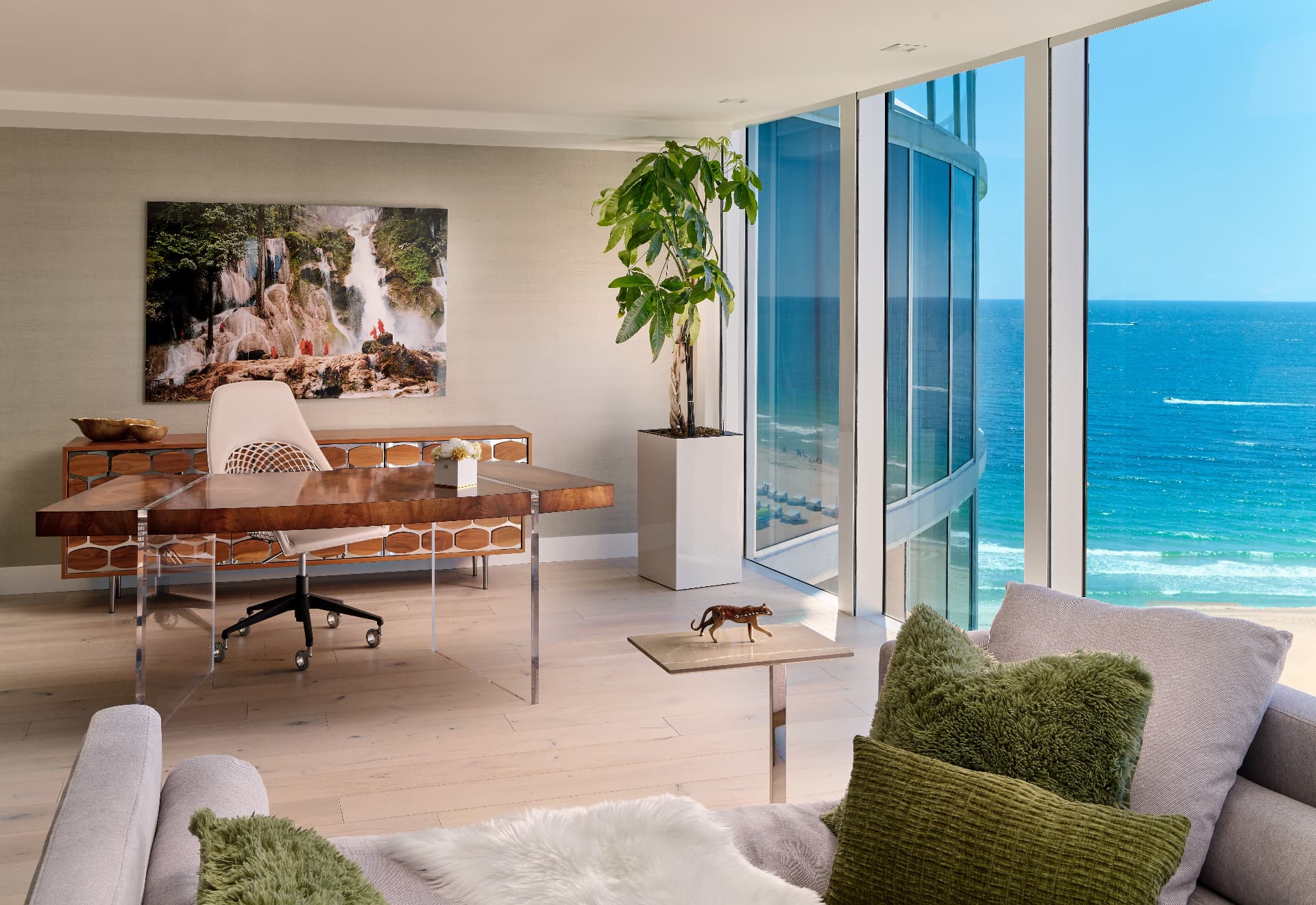 Oceanfront study designed by DawnElise Interiors with a burl wood and acrylic desk framed by floor-to-ceiling glass